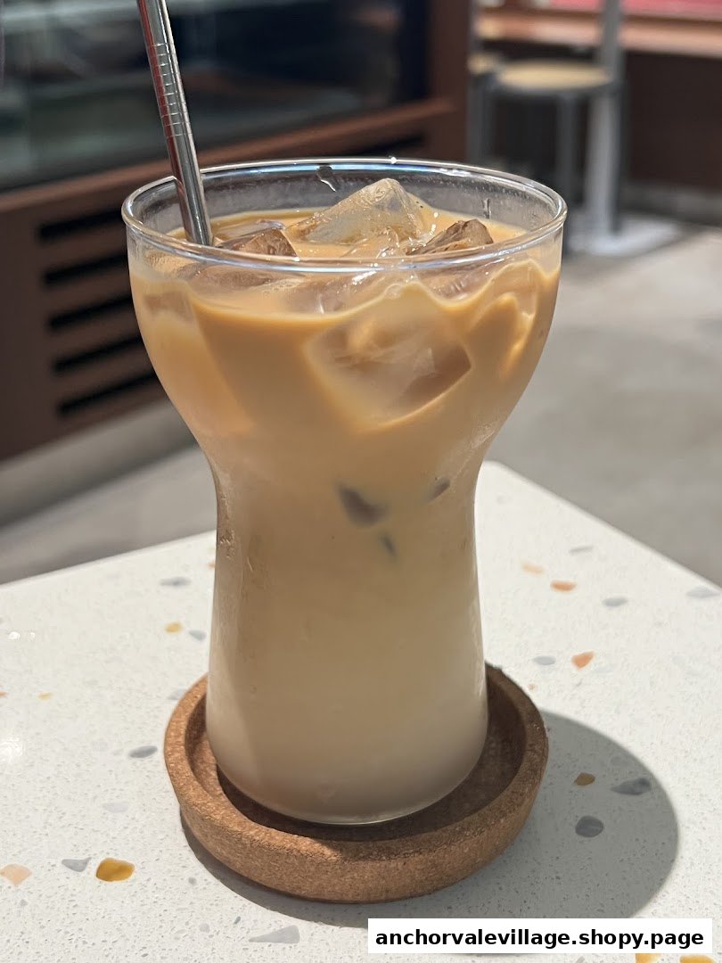 A refreshing iced latte with a metal straw on a speckled white table.