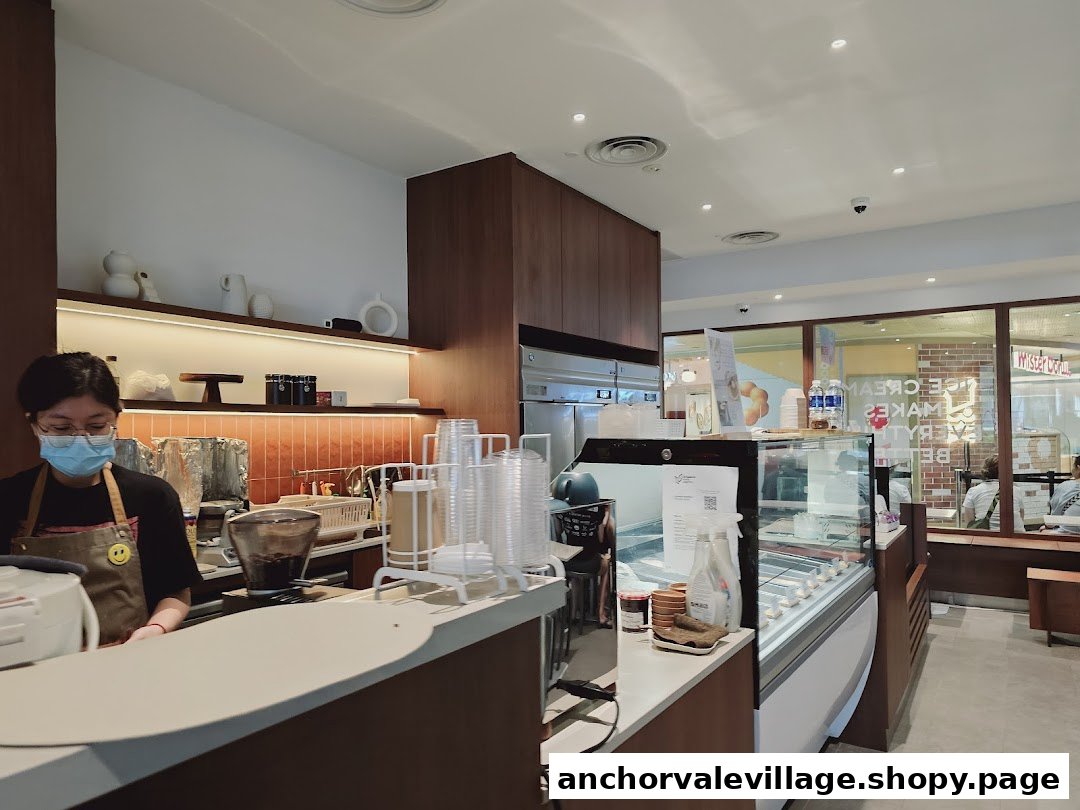 An interior view of The Better Scoop, featuring a staff member, counter, and ice cream display.