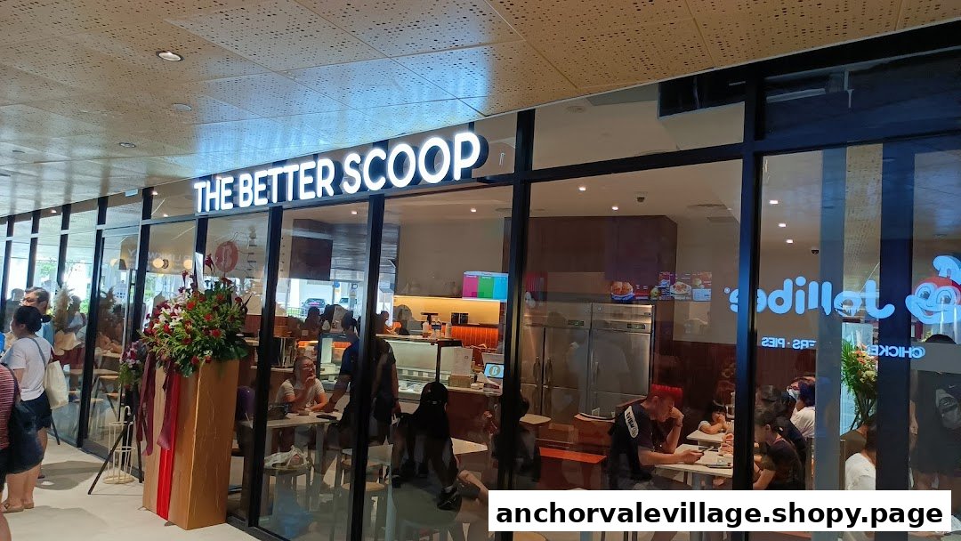 The exterior of 'The Better Scoop' ice cream shop with customers inside and a floral arrangement outside.