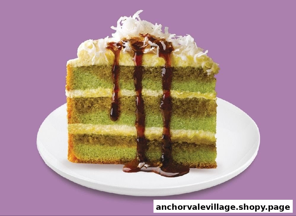 A slice of layered green cake with chocolate drizzle and coconut flakes on a white plate.
