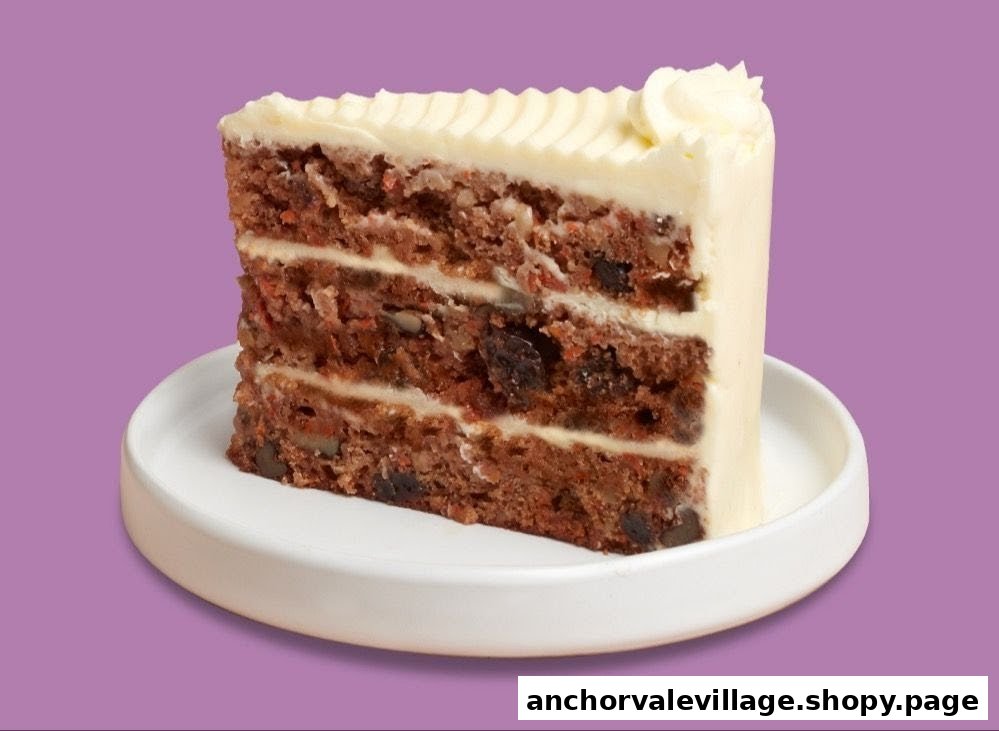 A delicious slice of multi-layered carrot cake with cream cheese frosting on a white plate.