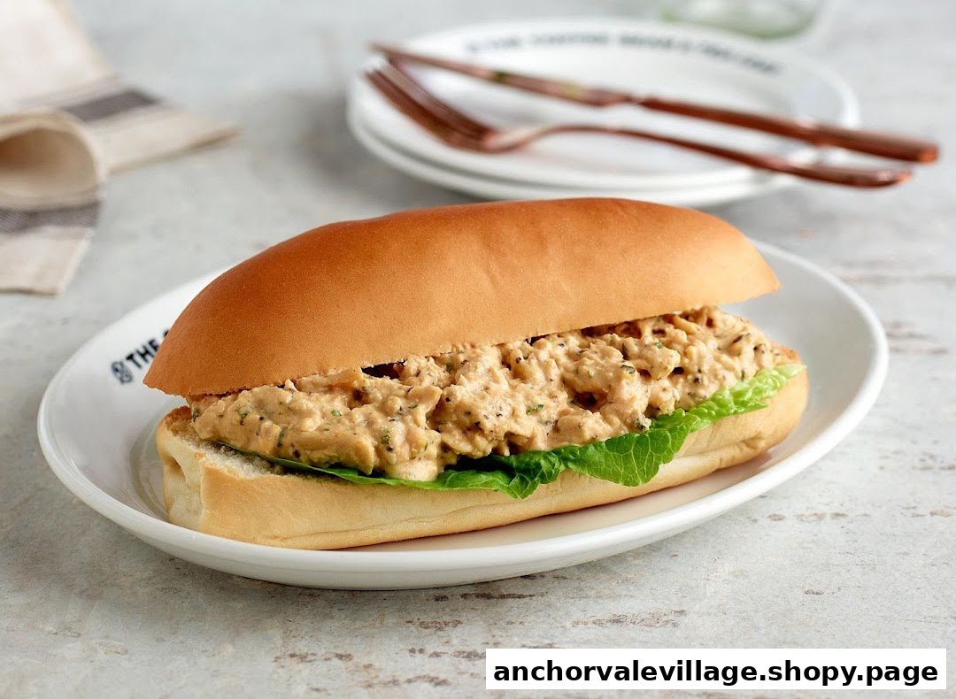A savory sandwich with creamy filling and lettuce on a bun, served on a white plate.