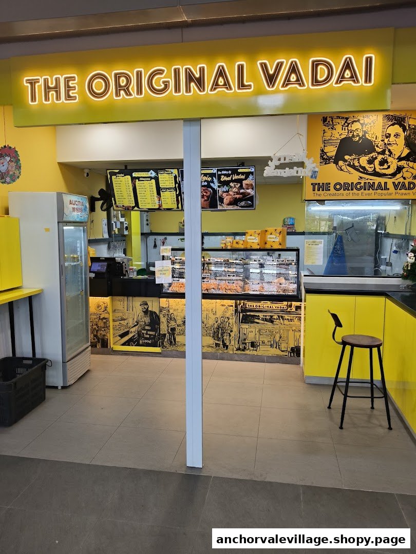The bright yellow shop front of 'The Original Vadai' with illuminated signage and a display counter.