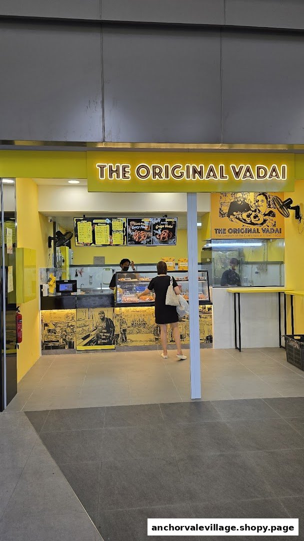 The brightly lit yellow shop front of The Original Vadai, with a customer at the counter.