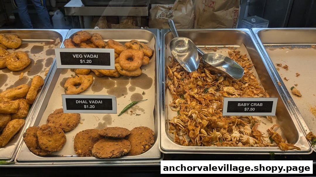 A display counter showcasing various vadai and crispy baby crab dishes with their prices.