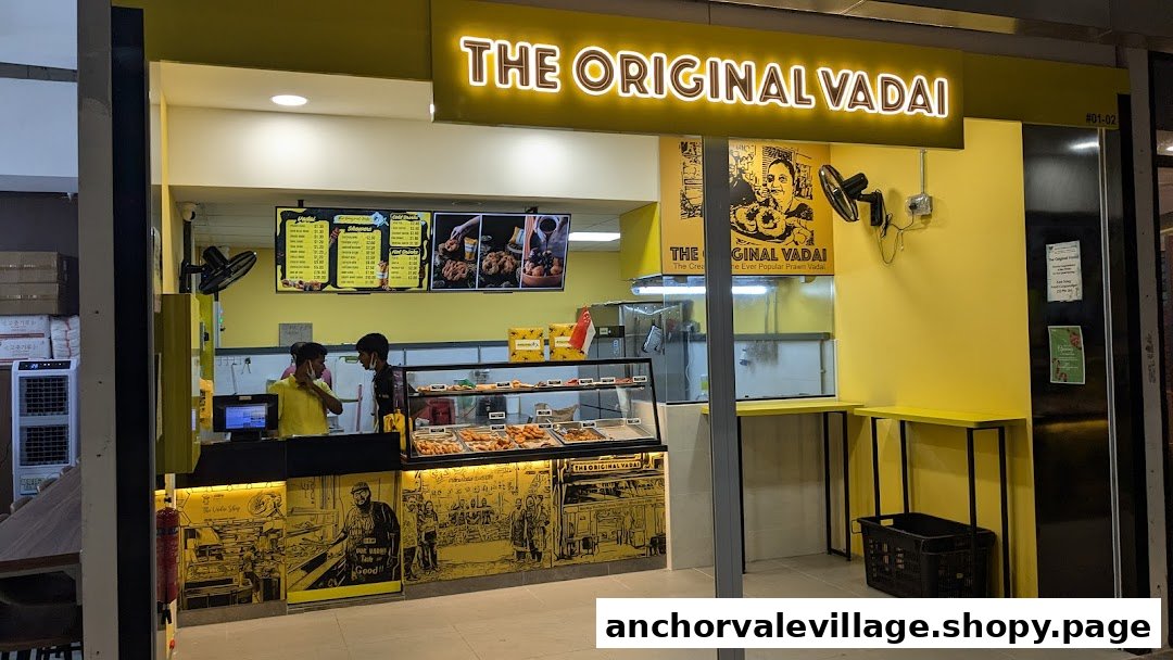 The bright yellow storefront of The Original Vadai, featuring staff, a display counter, and menu boards.
