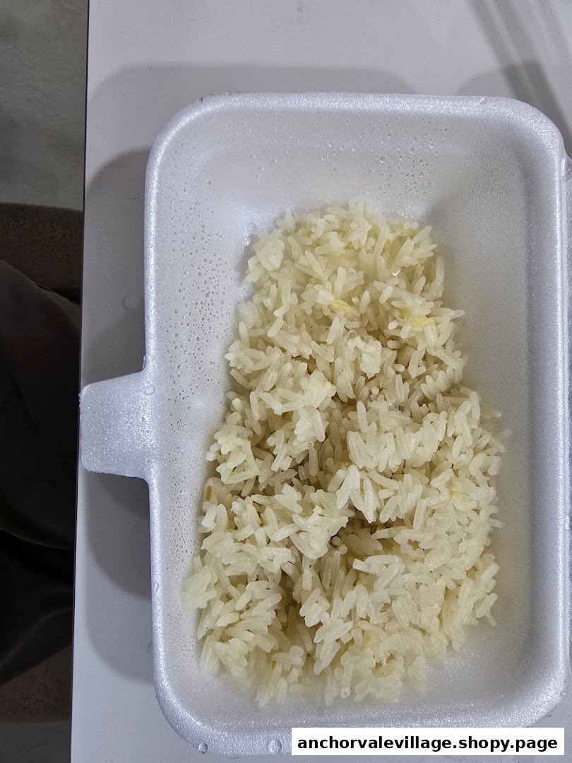 A close-up of fragrant chicken rice served in a white takeaway container.