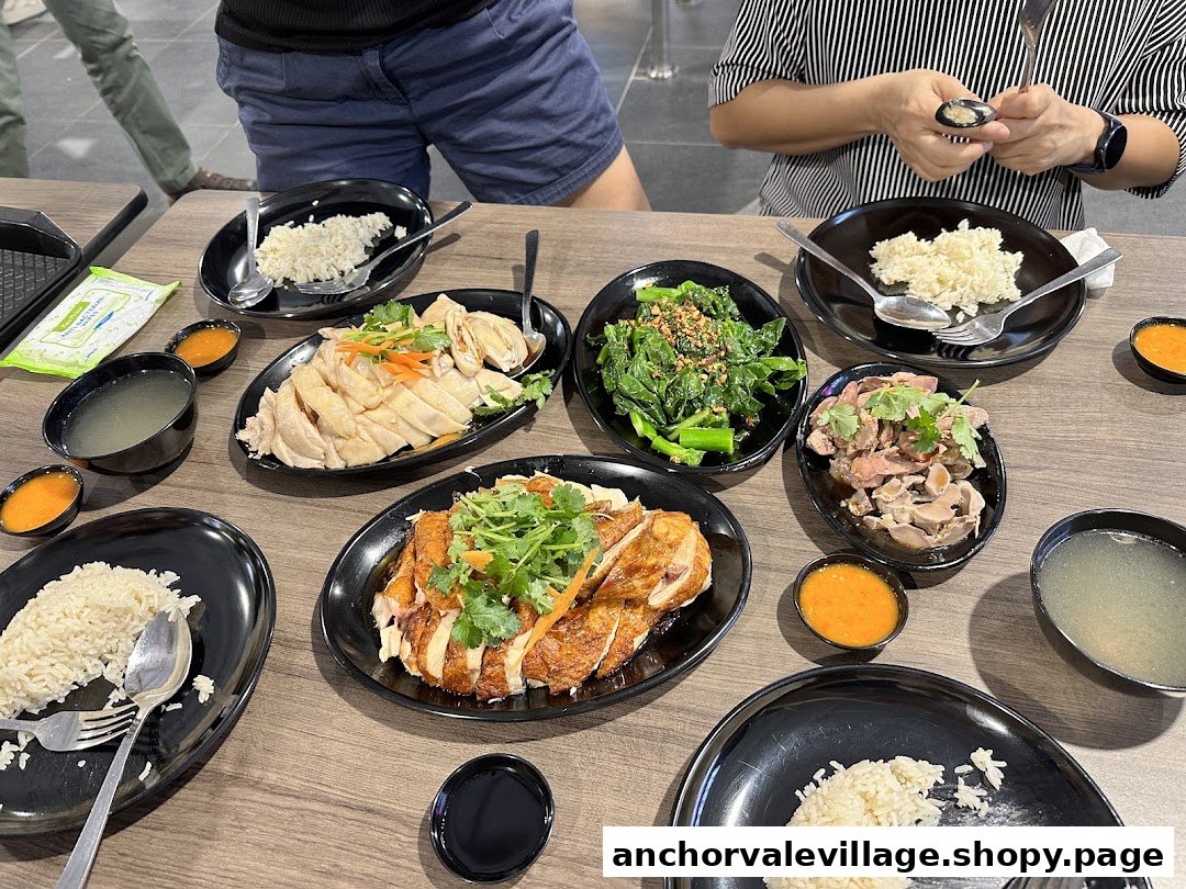 A table laden with various chicken rice dishes, including steamed and roasted chicken, side dishes, and soup, with diners.