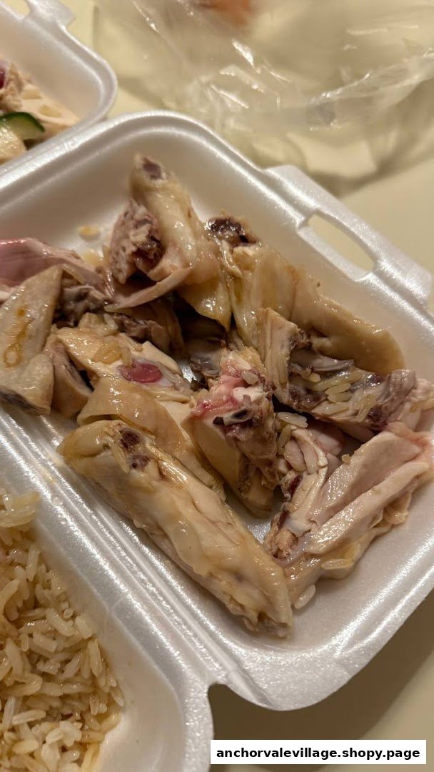 A close-up of succulent chicken pieces in a takeaway container, part of a chicken rice meal.
