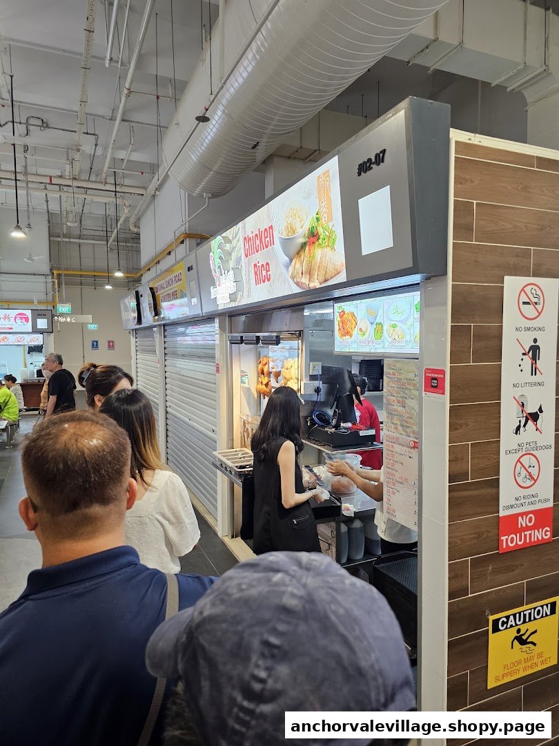 Customers queueing at Uncle Louis Famous Chicken Rice stall in a bustling food court.