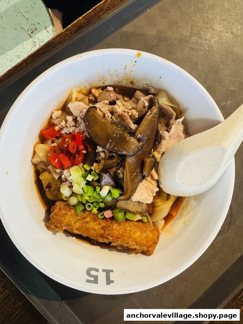 A close-up of a delicious bowl of noodles with various toppings and a spoon.
