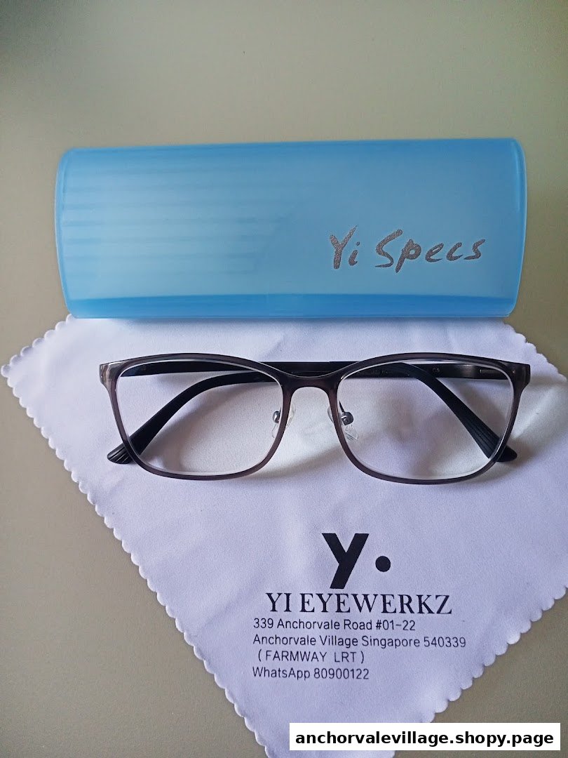 A pair of eyeglasses, a blue case, and a branded cleaning cloth with shop contact details.