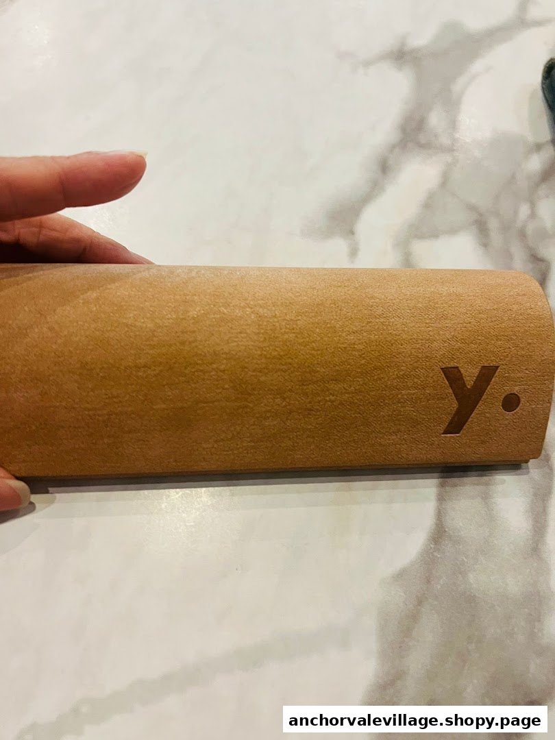 A close-up of a stylish brown eyewear case with the 'Y.' logo, resting on a marble surface.