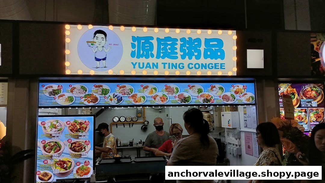 The illuminated storefront of Yuan Ting Congee, featuring its signboard, food display panels, and staff serving customers.