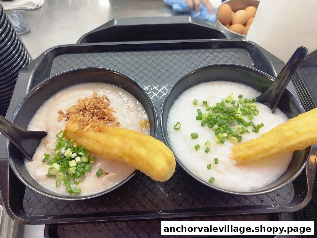 Two bowls of congee with various toppings and fried dough sticks on a serving tray.