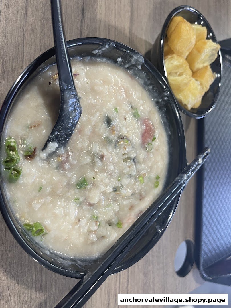 A comforting bowl of congee with toppings and a side of crispy fried dough sticks.