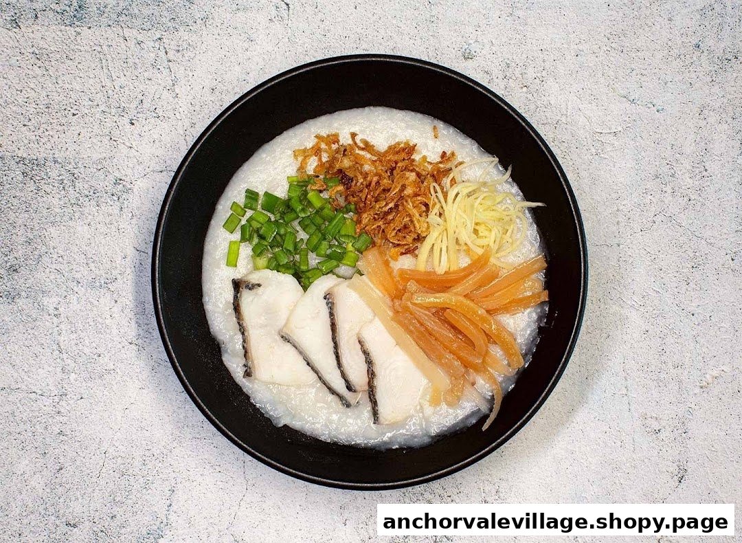 A bowl of congee topped with fish slices, fried shallots, spring onions, and shredded ginger.
