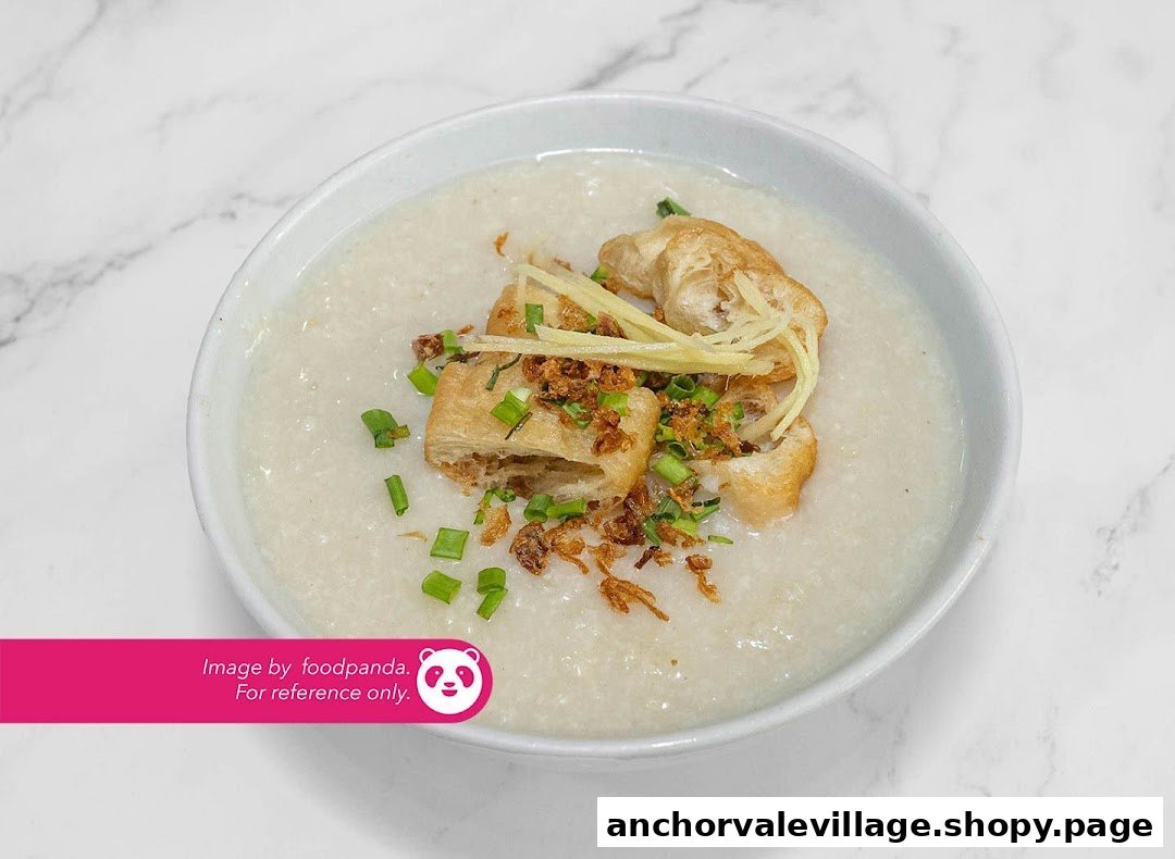 A comforting bowl of congee topped with fried dough, ginger, fried shallots, and spring onions.