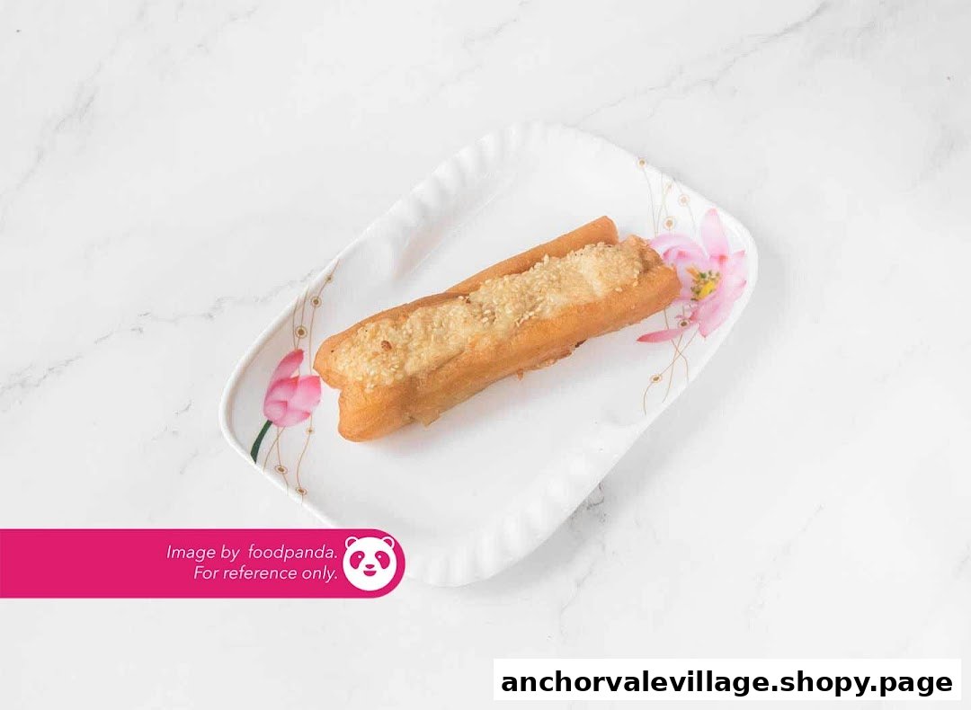 A golden-brown fried dough stick topped with sesame seeds on a white plate with floral design.