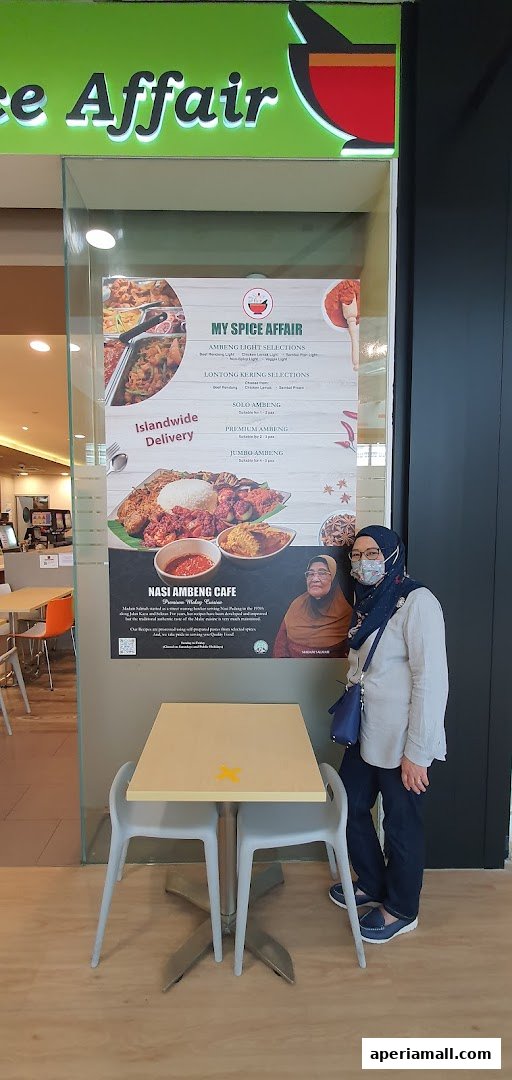 A woman stands next to a display menu outside the FM FoodMaster shop.