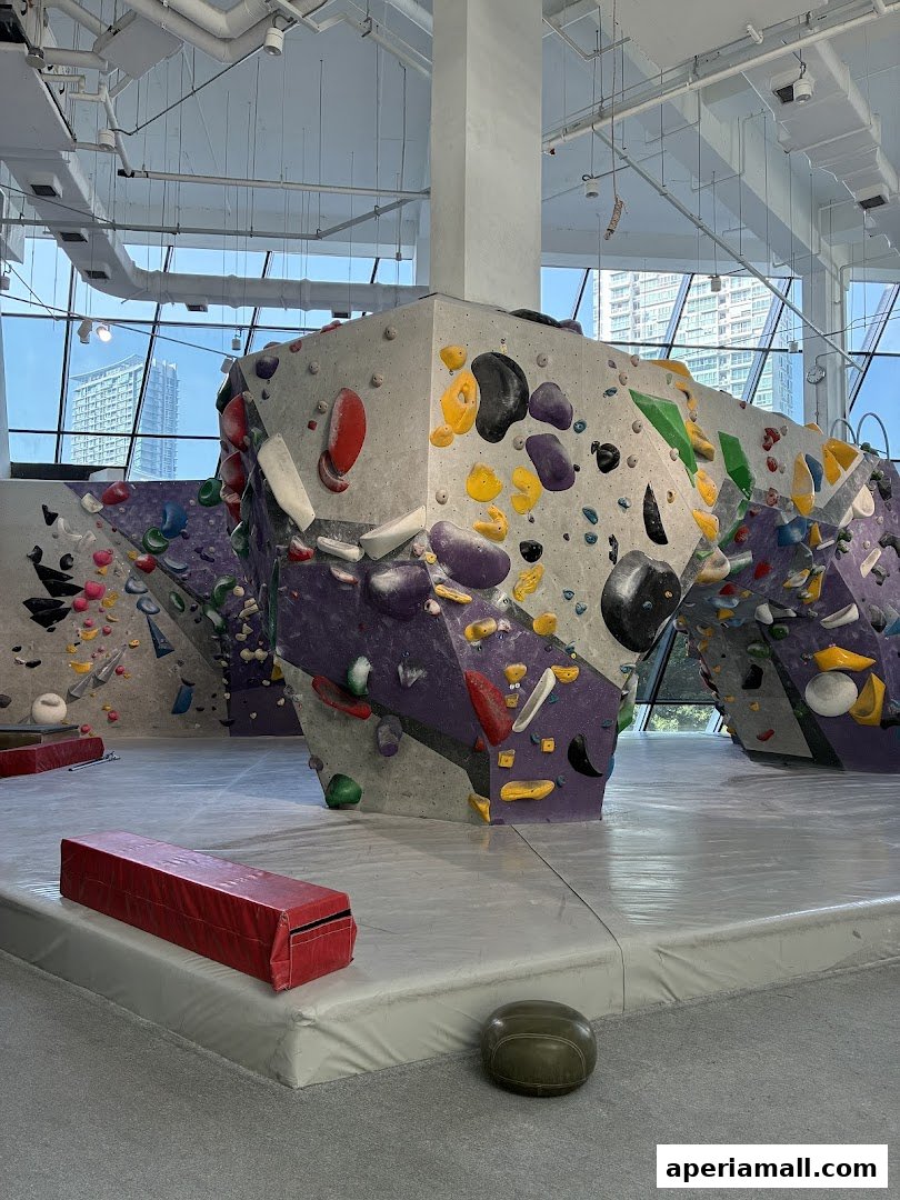 Interior of a bouldering gym with colorful climbing walls and safety mats.