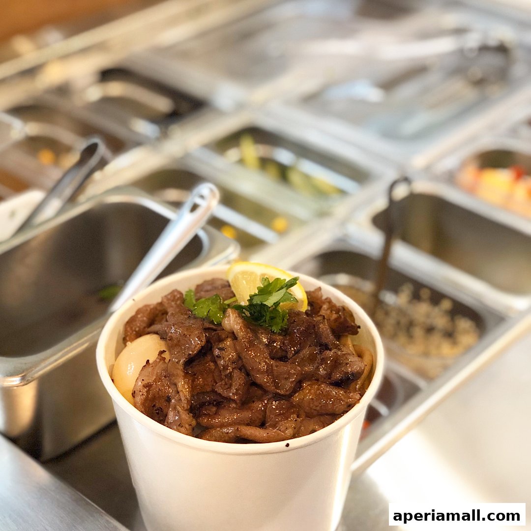 A white cup filled with seasoned meat, garnished with lemon and parsley, in a salad bar setting.