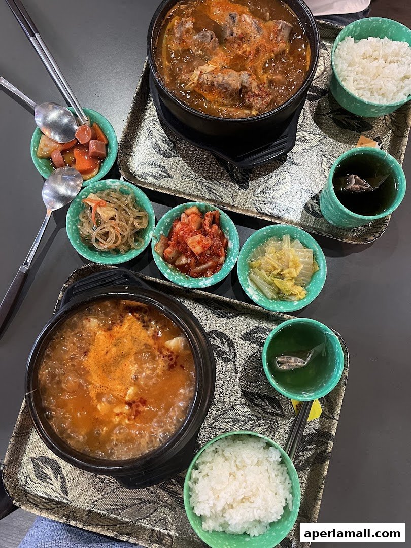 Two steaming Korean stews served with rice, kimchi, and other side dishes.