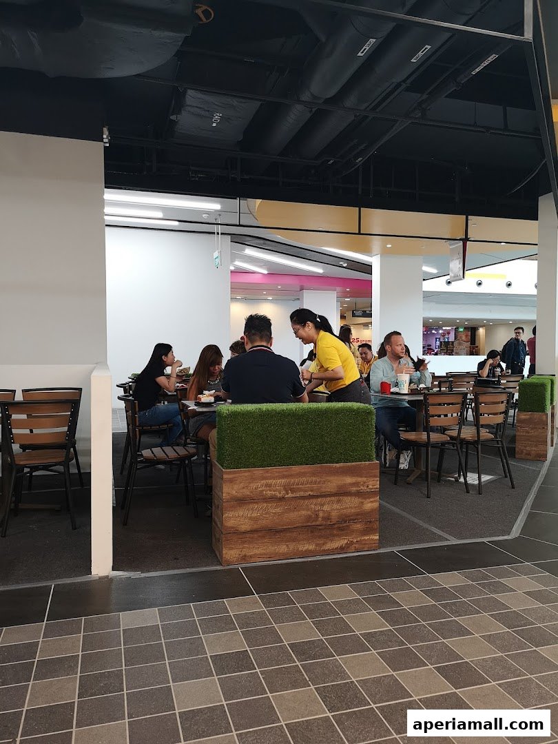Diners seated at tables inside a McDonald's restaurant, with a staff member serving.