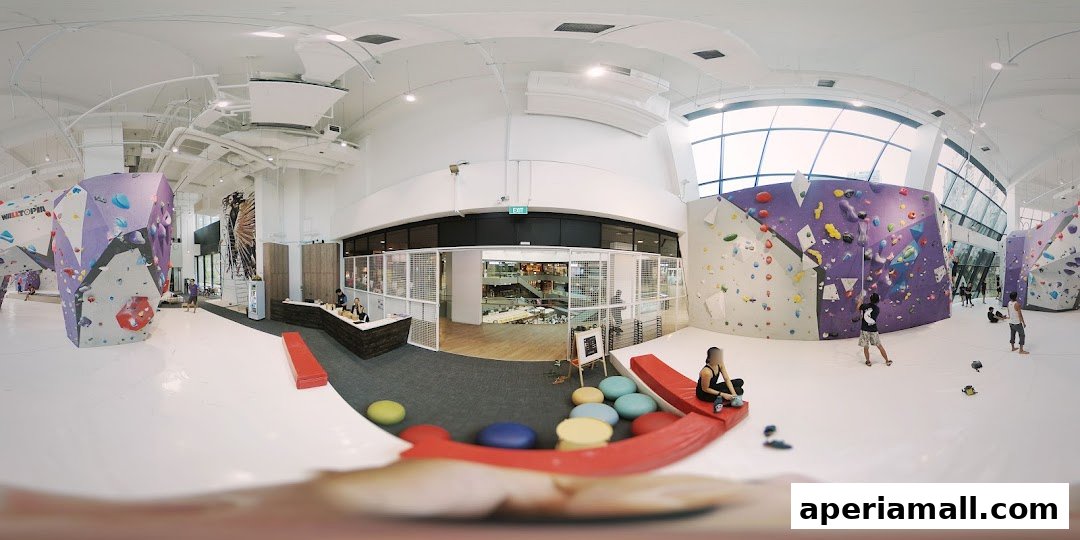 Interior view of a modern bouldering gym with colorful climbing walls and people climbing.