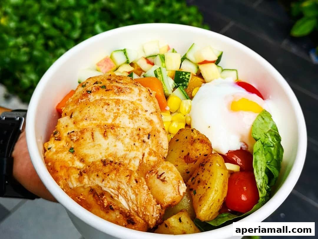 A close-up of a healthy salad bowl with grilled chicken, poached egg, and fresh vegetables.