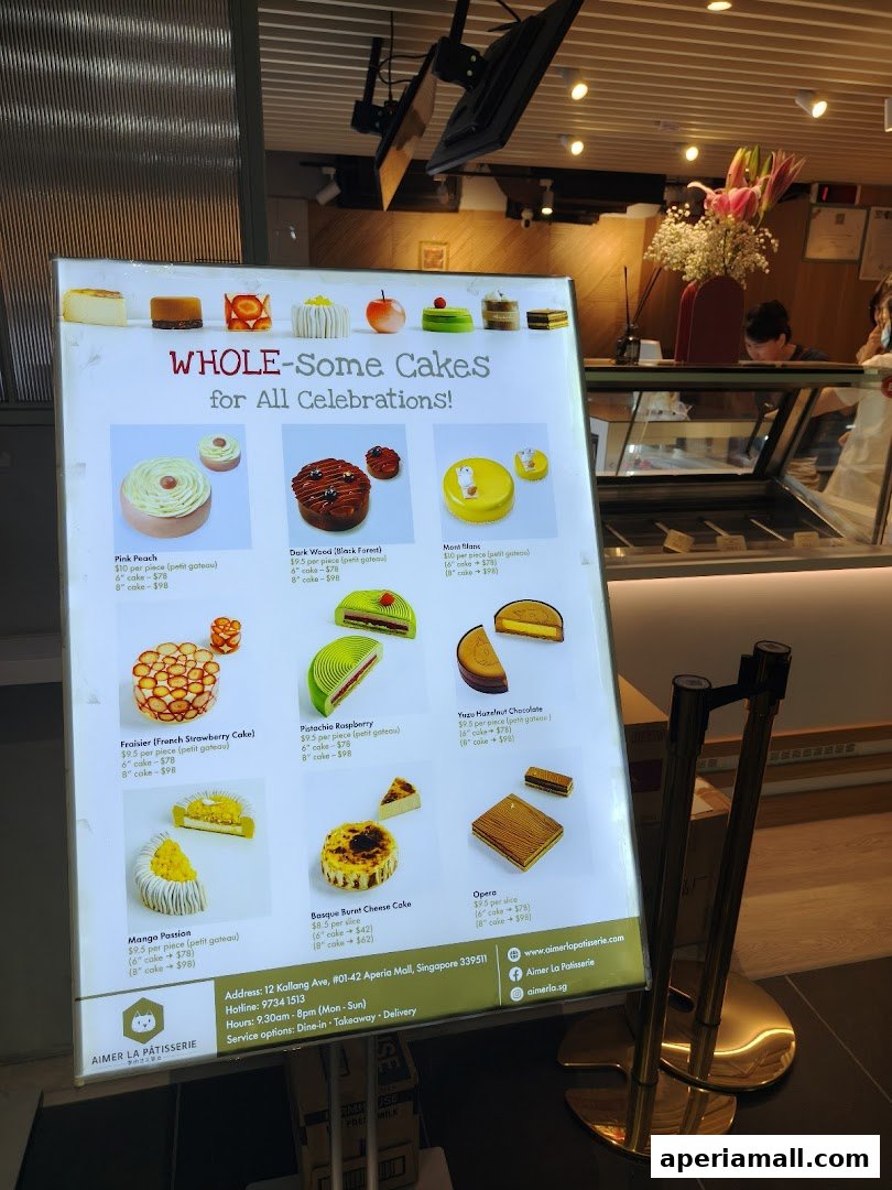 A brightly lit menu board showcasing various whole cakes and slices with prices.