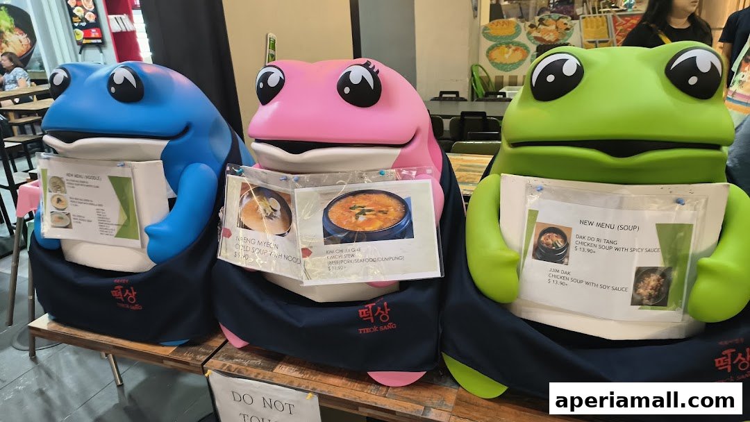 Three colorful frog mascots displaying menus for Korean dishes.