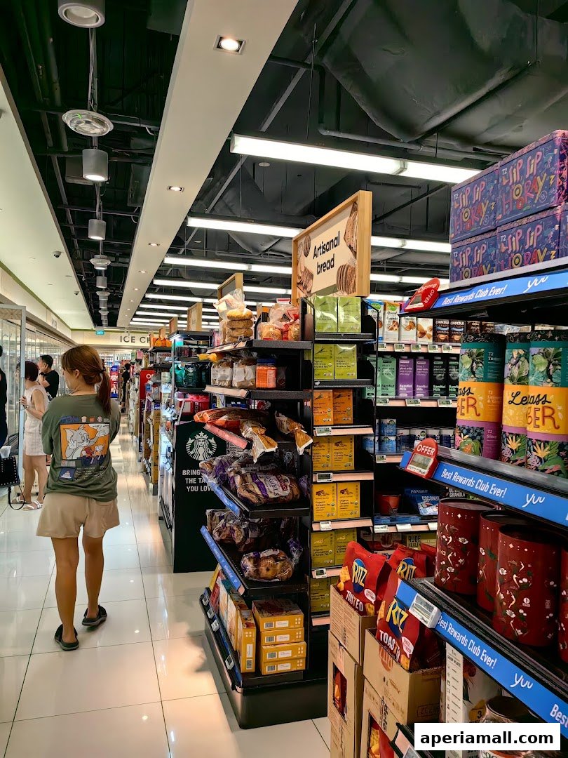 A shopper walks through a well-lit grocery store aisle filled with various food products and displays.