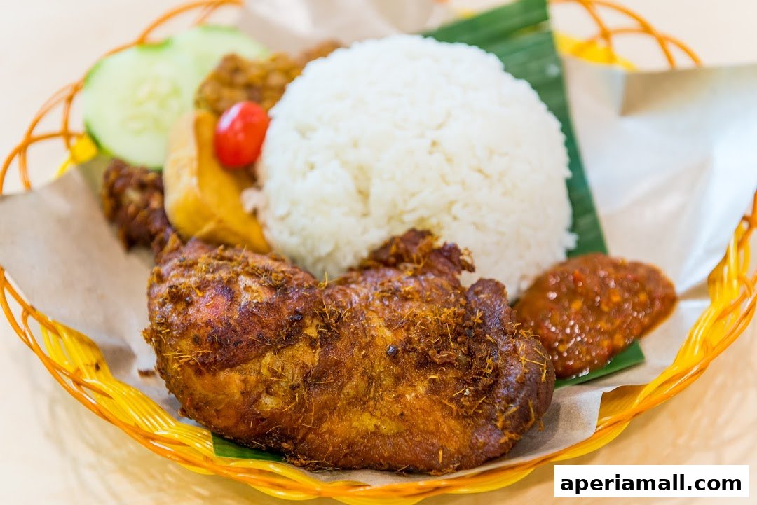 A delicious plate of fried chicken with rice, cucumber slices, and chili paste.