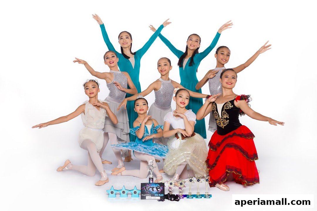 A group of young dancers in various costumes posing with trophies against a white background.