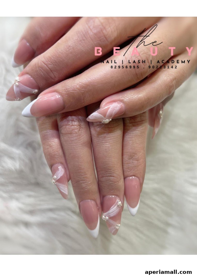 Close-up of hands with elegant French manicured nails adorned with pearls and white ribbon designs.