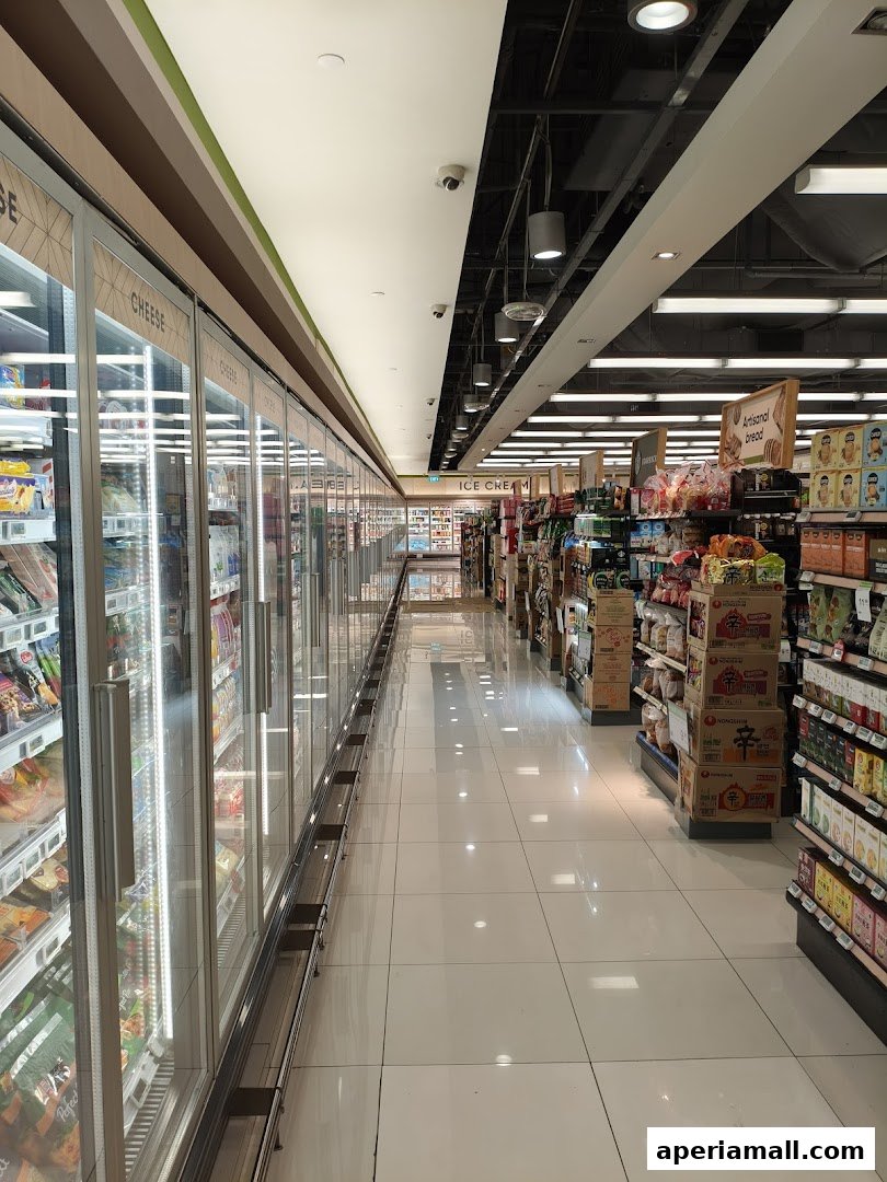 Aisle view of a well-lit supermarket with refrigerated display cases and shelves stocked with products.