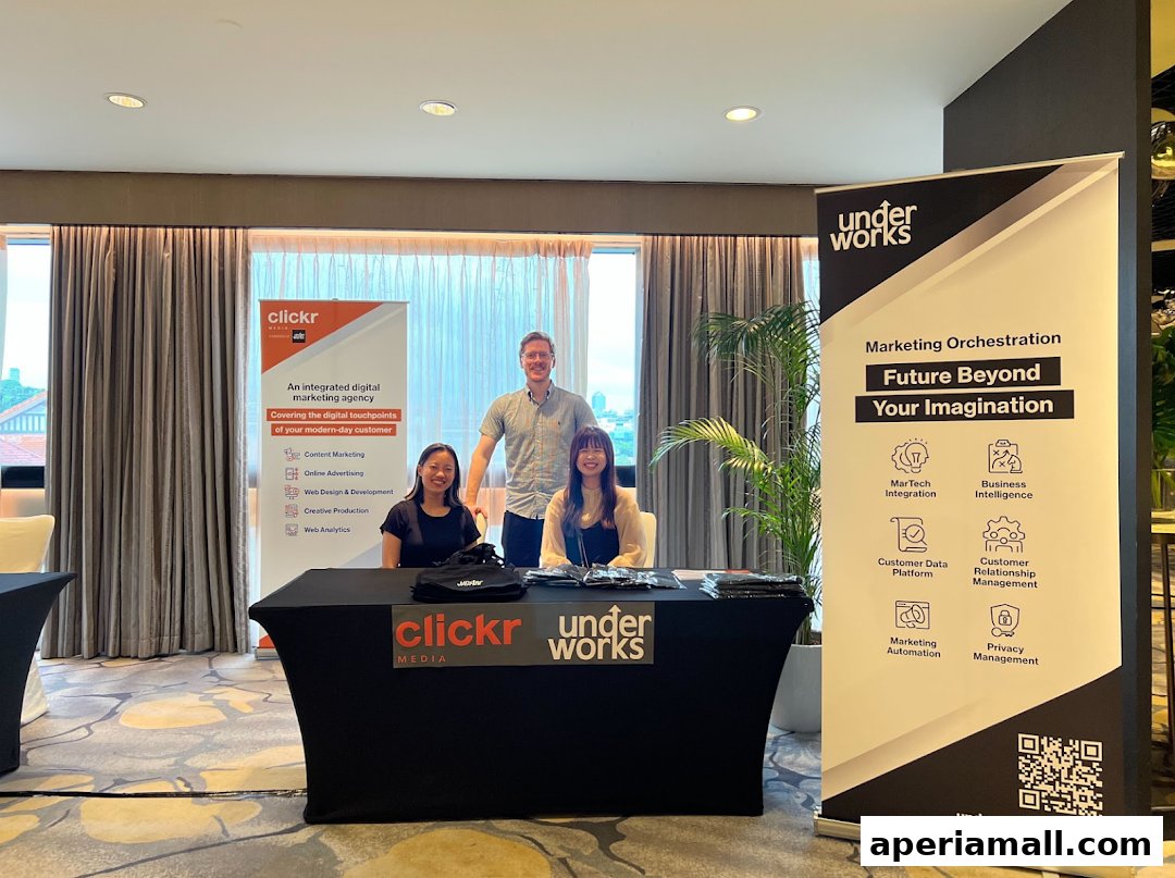 Three people stand behind a table with company banners promoting digital marketing services.