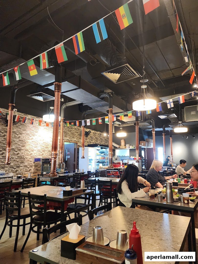 Interior of a restaurant with tables, chairs, and international flags decorating the ceiling.