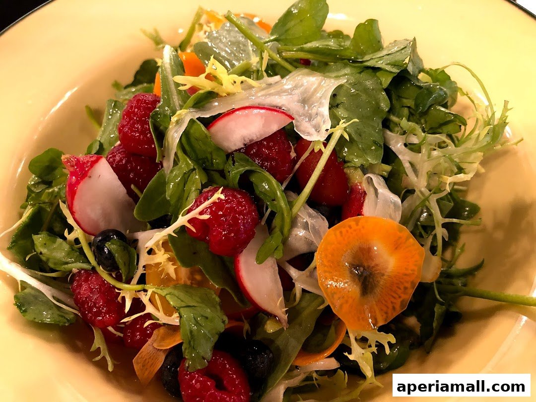 A vibrant salad with mixed greens, raspberries, blueberries, radishes, and a slice of orange vegetable.