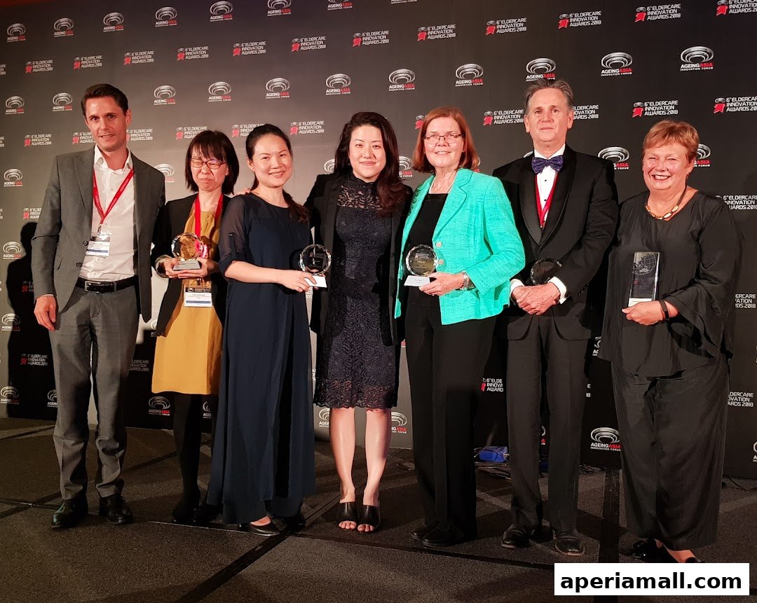 A group of six people posing for a photo at an awards ceremony, holding trophies.