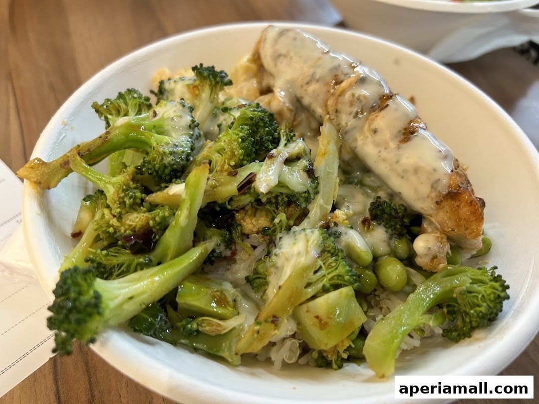 A close-up of a healthy salad bowl with grilled chicken, broccoli, edamame, and quinoa.