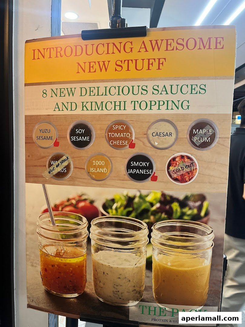 A sign advertising new sauces and kimchi topping at The Pack Protein & Salad Bar.