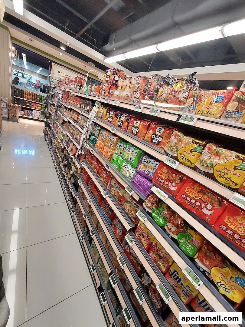 Aisle of instant noodles and snacks in a supermarket with clear price tags.