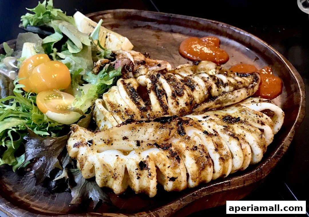 A wooden platter holds grilled calamari with a side salad and dipping sauce.