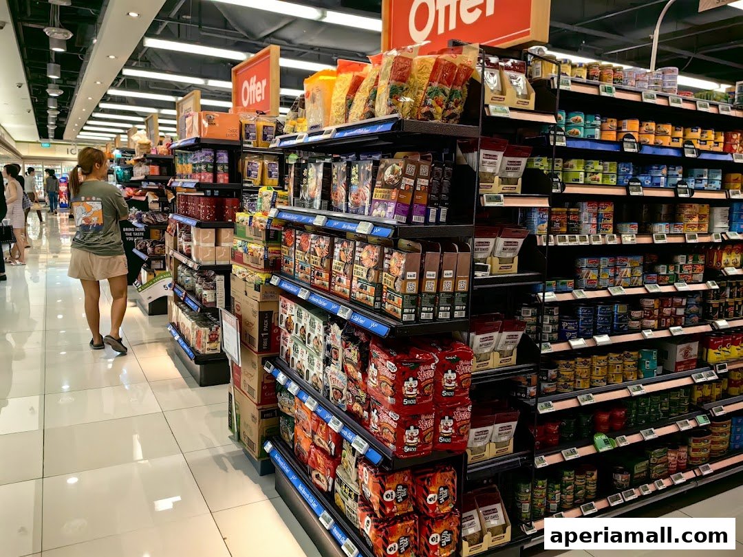 A shopper browses aisles stocked with various food products and canned goods in a supermarket.