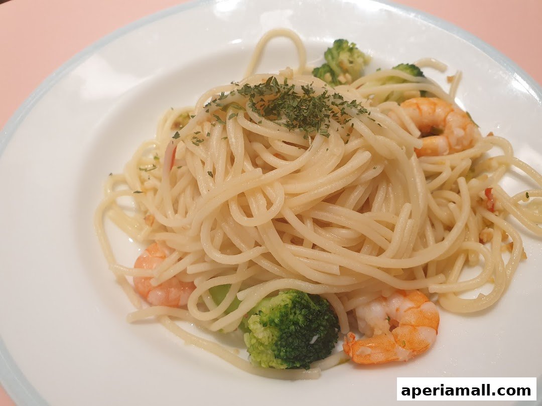 A plate of spaghetti with shrimp and broccoli, garnished with herbs.