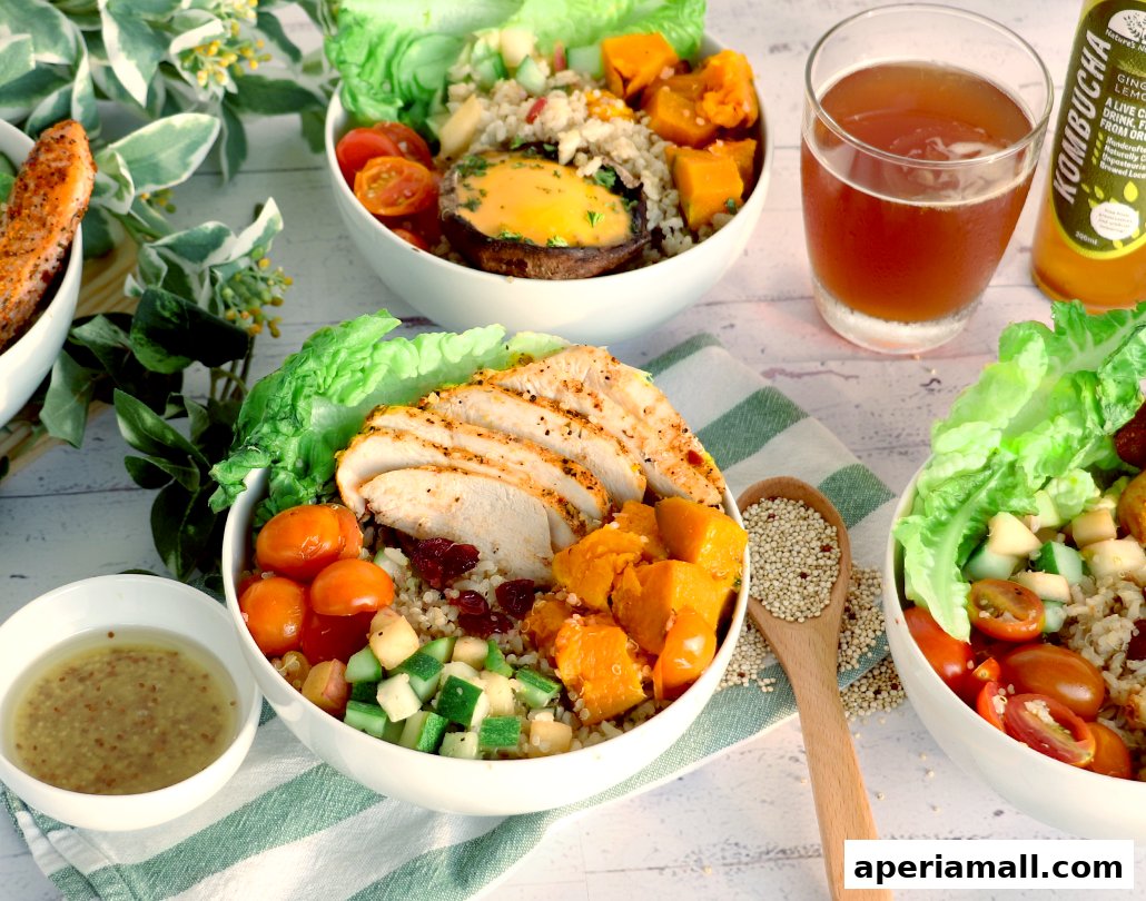 Three healthy salad bowls with chicken, salmon, and vegetables, plus a glass of kombucha.
