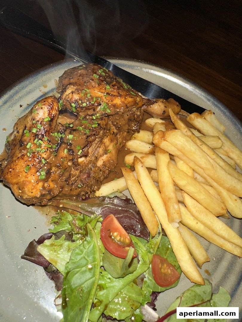 A plate of roasted chicken with fries and a side salad, steaming hot.