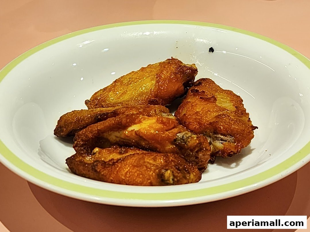 A bowl of crispy, golden-brown fried chicken wings with a light green rim.